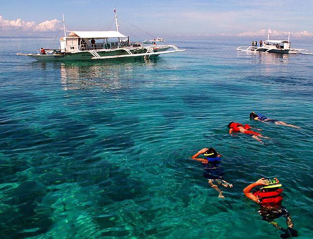 People snorkelling in the foreground, boats in the background